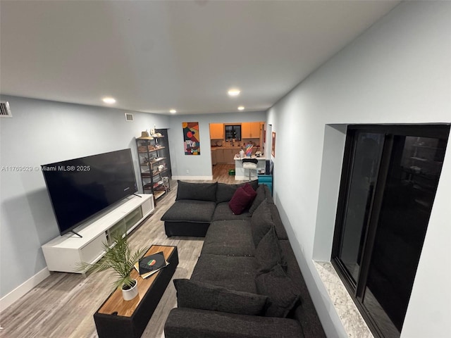 living room with light wood finished floors, recessed lighting, and baseboards