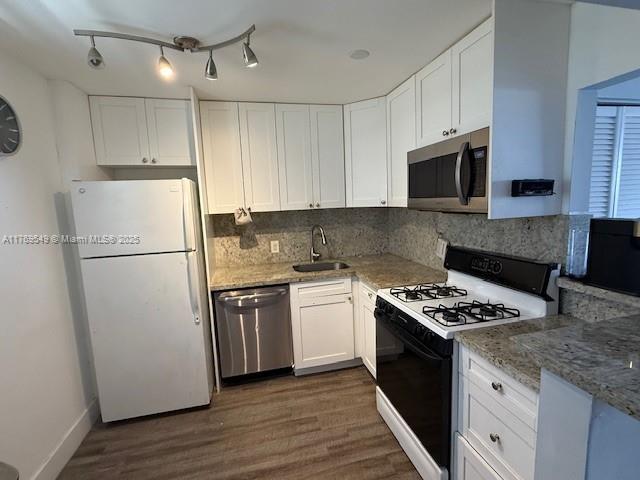 kitchen featuring decorative backsplash, white cabinetry, a sink, dark wood finished floors, and stainless steel appliances