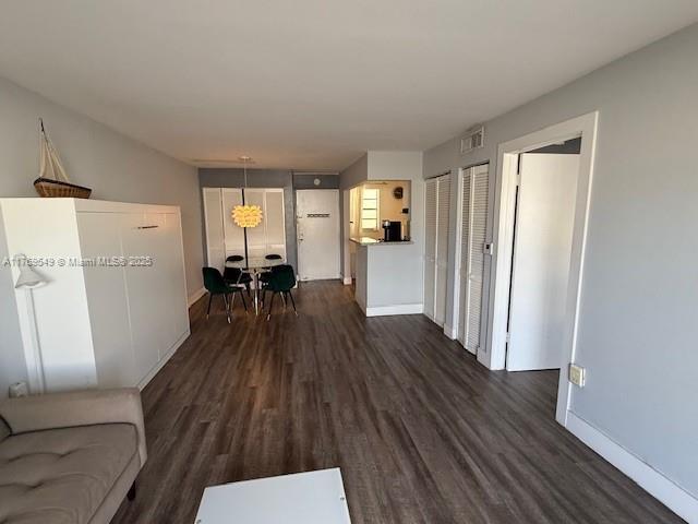 living room featuring baseboards, dark wood-style flooring, and visible vents