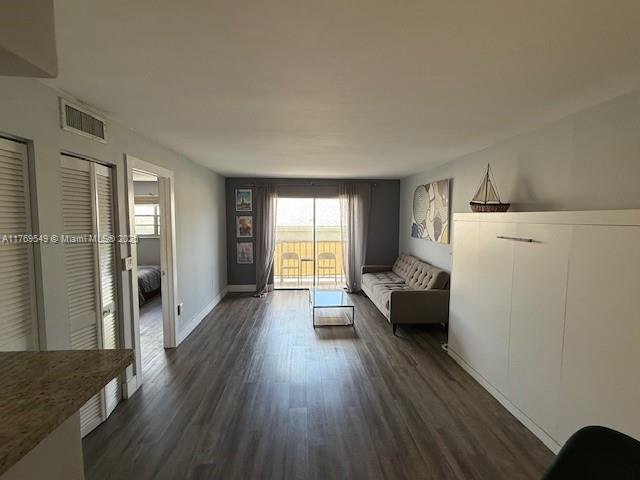 unfurnished room featuring visible vents, dark wood-style flooring, and baseboards