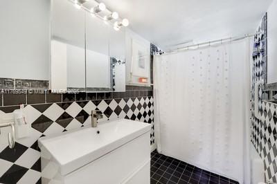 clothes washing area featuring dark tile patterned flooring and tile walls