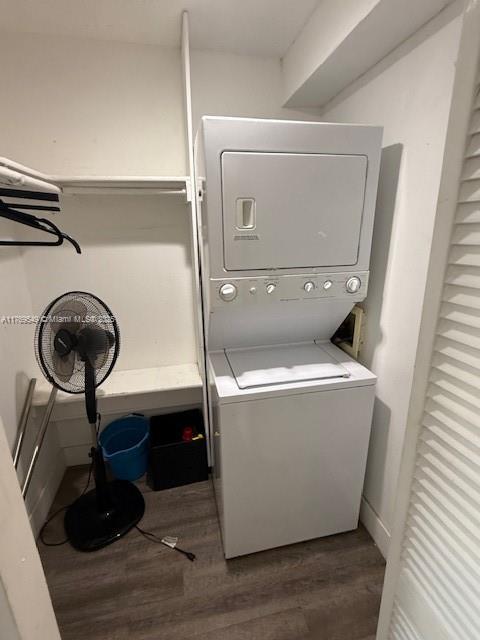 laundry room with stacked washing maching and dryer and wood finished floors