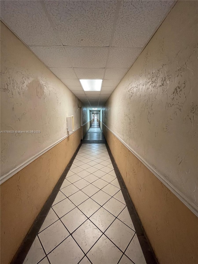 5775 W 20th Ave Unit 107, Hialeah, FL 33012 - hallway with light tile patterned flooring, a textured wall, and a paneled ceiling
