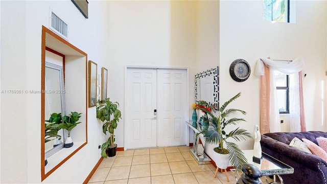 entrance foyer with a towering ceiling, baseboards, light tile patterned flooring, and visible vents