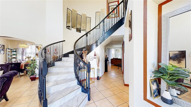 stairway featuring tile patterned floors, a towering ceiling, and arched walkways