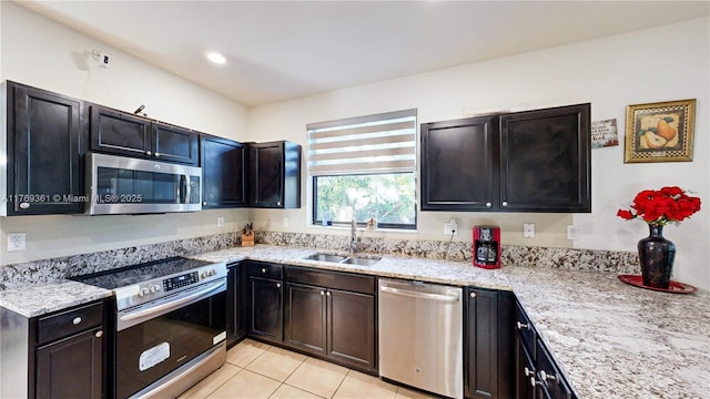 kitchen with recessed lighting, light tile patterned floors, a sink, light stone countertops, and appliances with stainless steel finishes