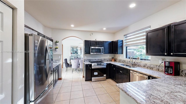 kitchen with stainless steel appliances, recessed lighting, arched walkways, a sink, and light tile patterned floors