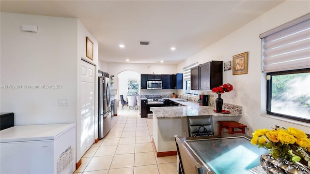 kitchen featuring light tile patterned flooring, visible vents, a peninsula, stainless steel appliances, and a sink