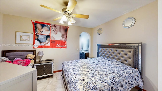 bedroom featuring a ceiling fan, arched walkways, and baseboards
