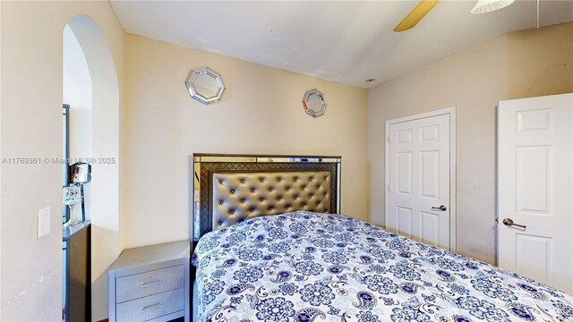 bedroom with arched walkways and ceiling fan