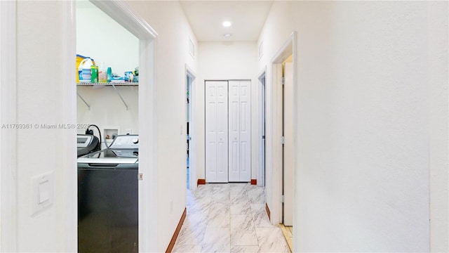 hall featuring baseboards, marble finish floor, and washer and clothes dryer
