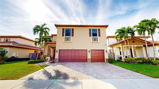 mediterranean / spanish home featuring stucco siding, stone siding, decorative driveway, a front lawn, and a garage