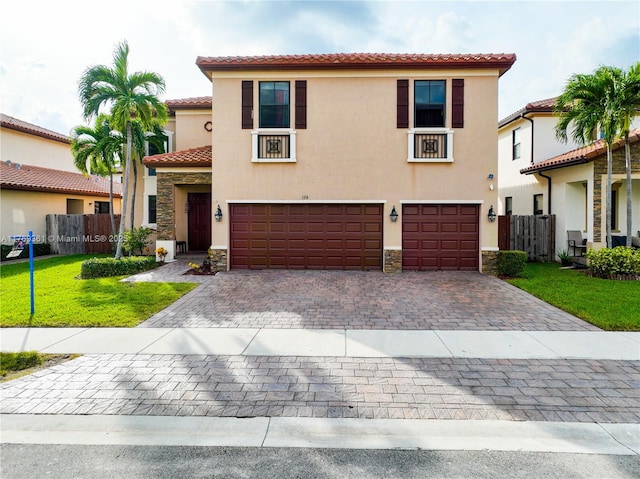 mediterranean / spanish-style home with a tile roof, stucco siding, stone siding, and a garage