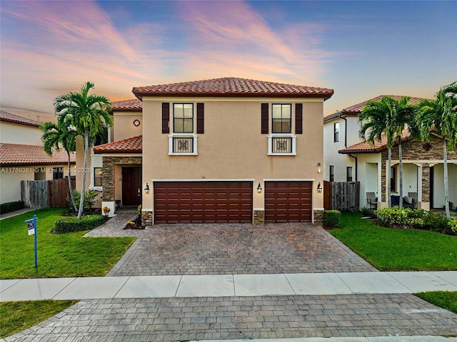 mediterranean / spanish-style house featuring stucco siding, stone siding, a tiled roof, and fence