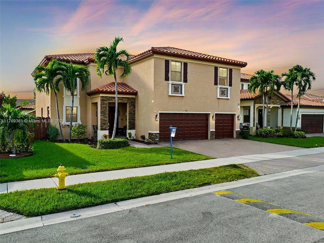mediterranean / spanish-style home featuring stone siding, decorative driveway, a garage, a tile roof, and stucco siding
