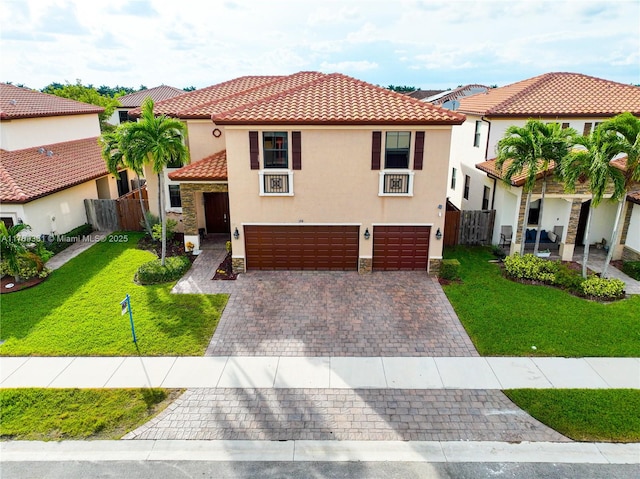 mediterranean / spanish-style home with a tiled roof, a front yard, decorative driveway, and an attached garage