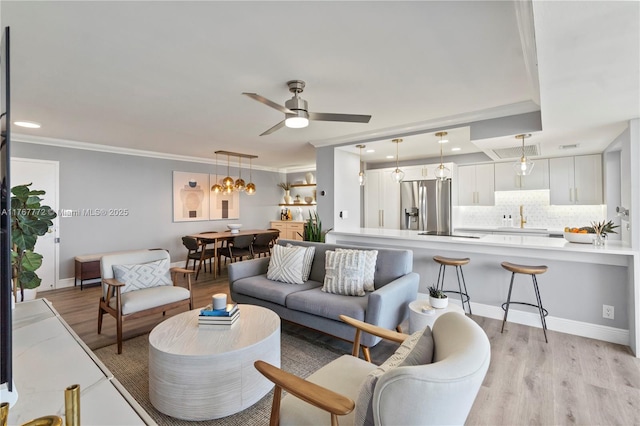 living room featuring baseboards, crown molding, light wood-style flooring, and ceiling fan