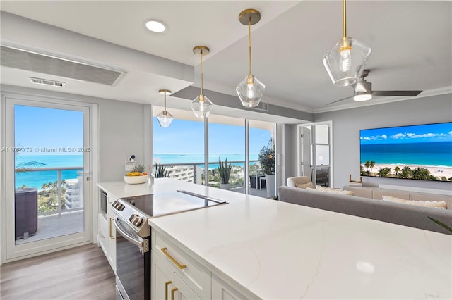 kitchen featuring a wealth of natural light, open floor plan, electric range, and white cabinetry