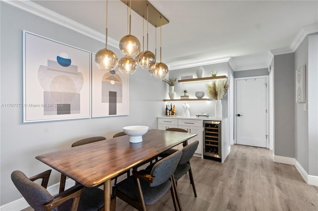 dining area featuring light wood-type flooring, ornamental molding, baseboards, wine cooler, and bar