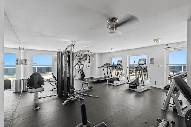 exercise room featuring baseboards, a healthy amount of sunlight, and a ceiling fan