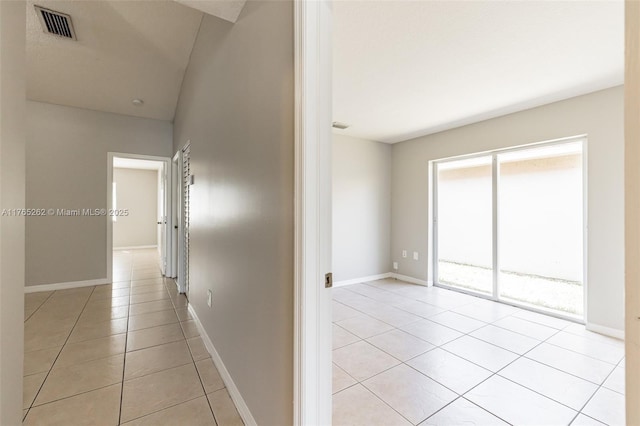 hallway with light tile patterned flooring, baseboards, and visible vents