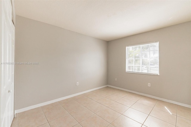empty room with light tile patterned floors and baseboards
