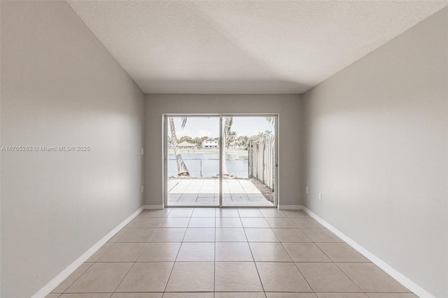 spare room featuring light tile patterned flooring, baseboards, and a textured ceiling