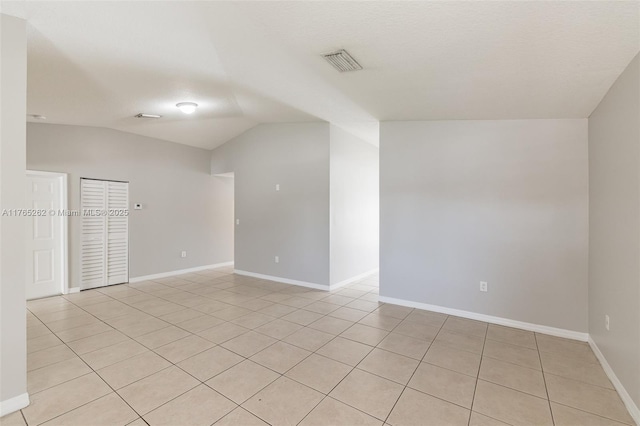 empty room featuring baseboards, visible vents, and vaulted ceiling