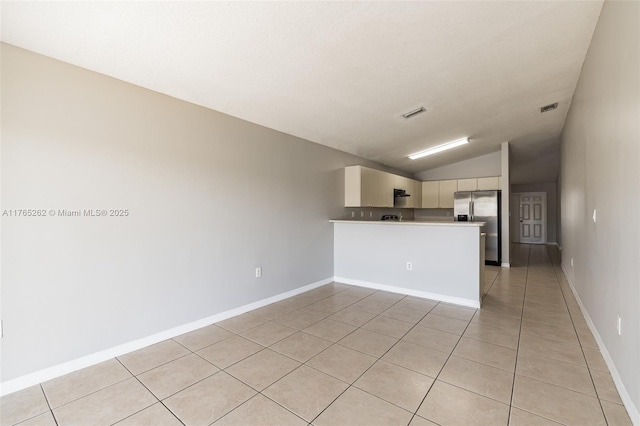 interior space with light tile patterned flooring, baseboards, lofted ceiling, and visible vents