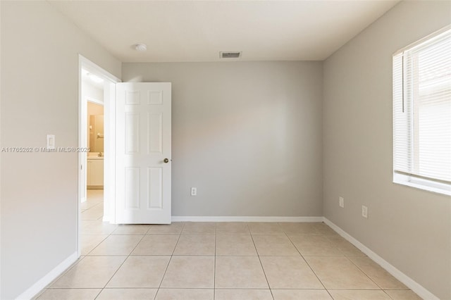 empty room featuring light tile patterned floors, baseboards, and visible vents