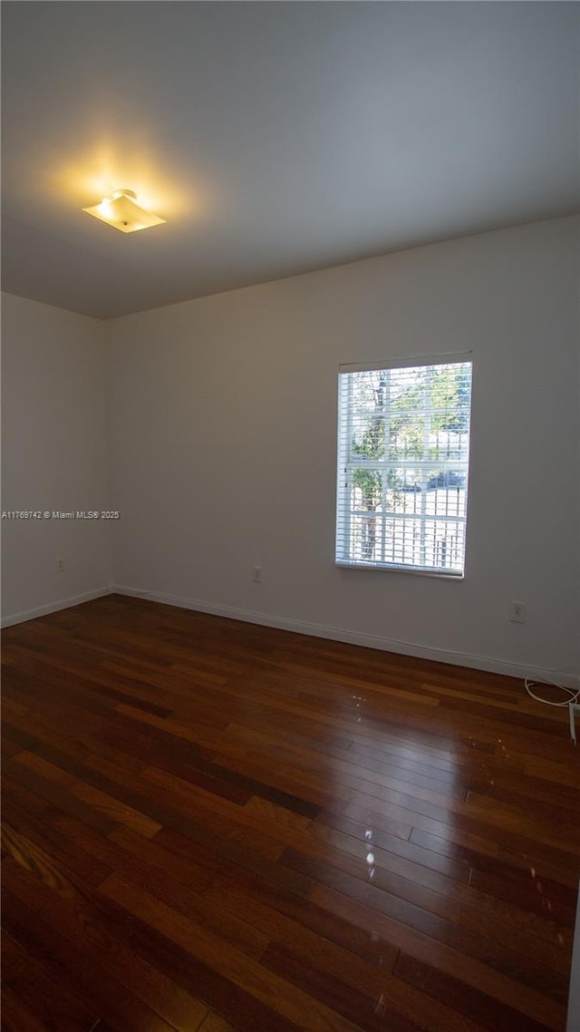 unfurnished room featuring dark wood-type flooring and baseboards