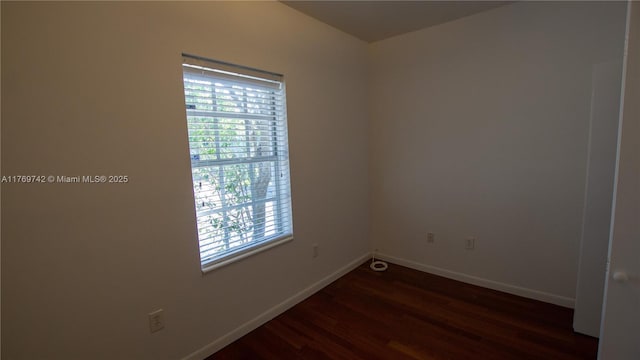empty room featuring baseboards and dark wood finished floors