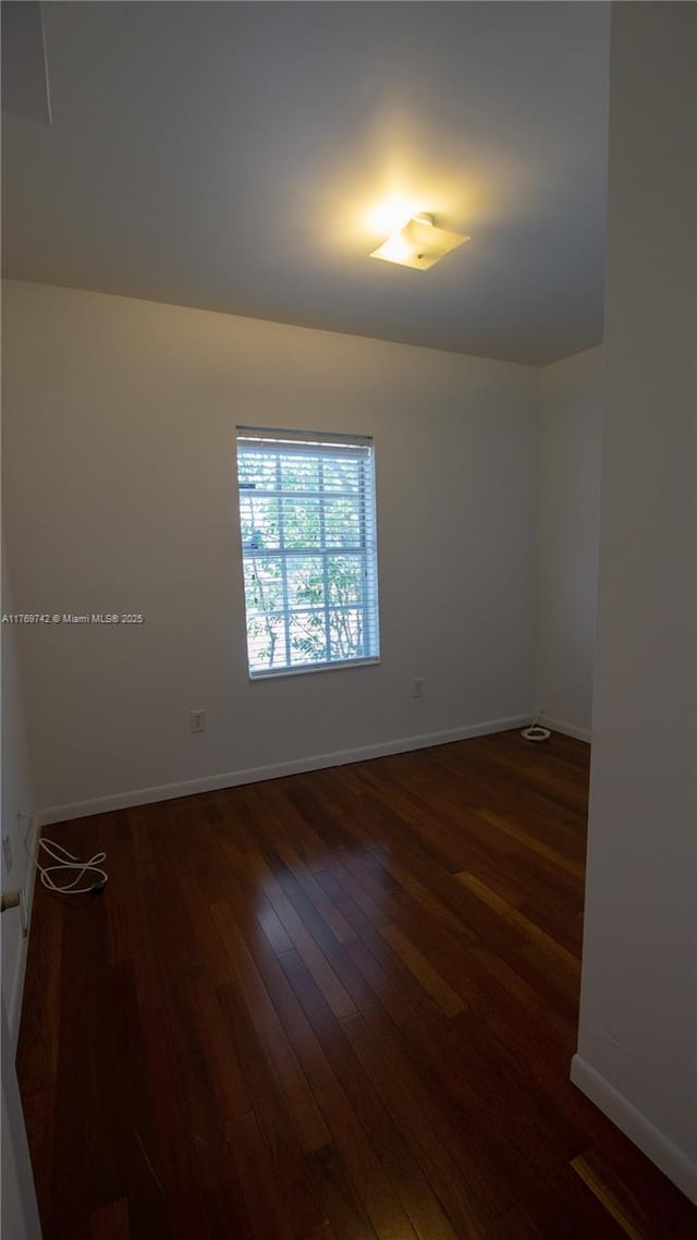 unfurnished room with baseboards and hardwood / wood-style floors