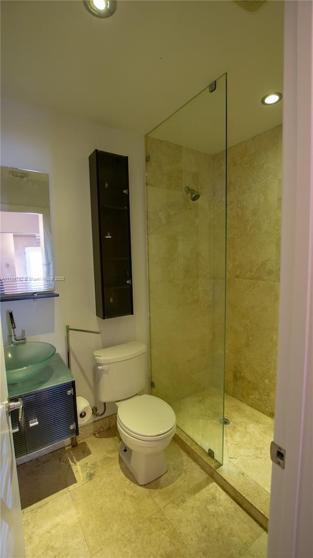 full bathroom featuring a tile shower, recessed lighting, toilet, and vanity