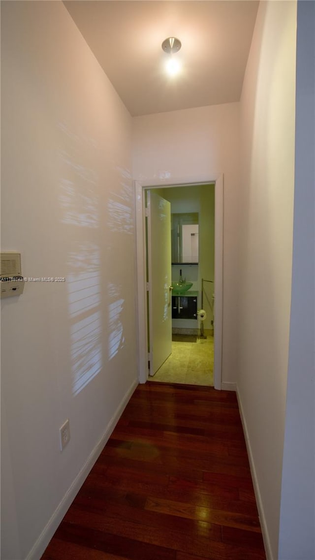 hallway featuring baseboards and wood finished floors