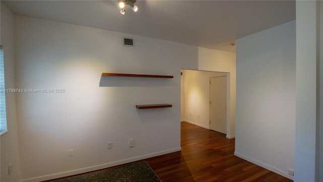 spare room featuring baseboards, visible vents, and wood finished floors