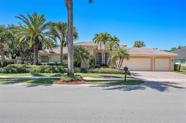 2541 Golf View Dr, Weston, FL 33327 - mediterranean / spanish-style house with stucco siding, a tile roof, decorative driveway, and an attached garage