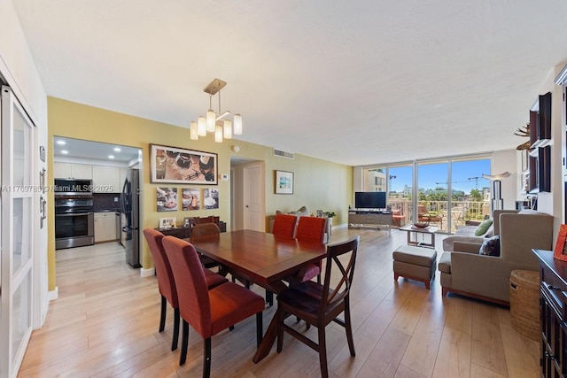 dining space featuring visible vents, floor to ceiling windows, light wood-style flooring, and a chandelier