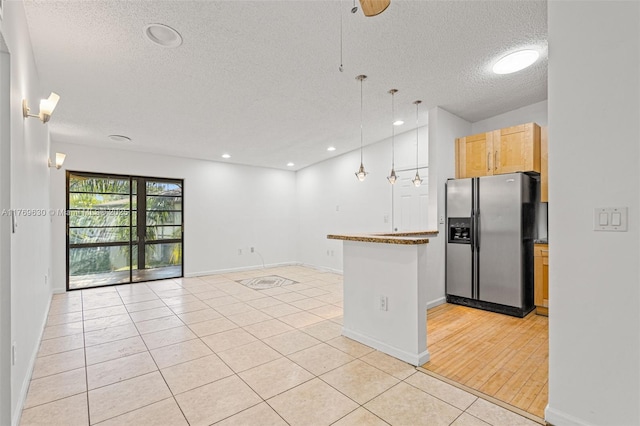 915 NE 199th St Unit 202-15, Miami, FL 33179 - kitchen featuring a peninsula, stainless steel refrigerator with ice dispenser, open floor plan, hanging light fixtures, and light tile patterned floors