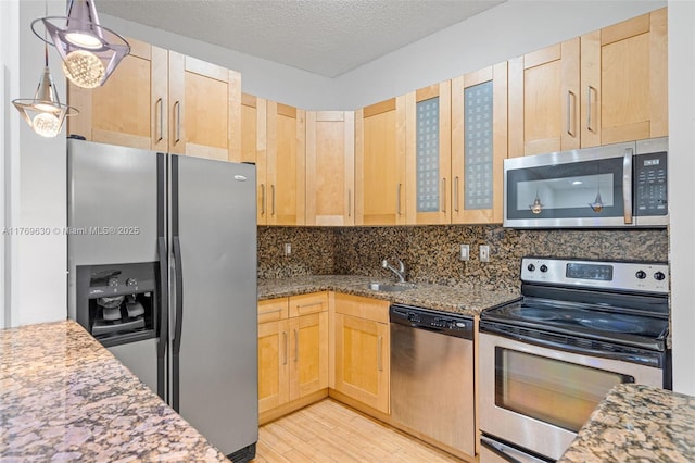 915 NE 199th St Unit 202-15, Miami, FL 33179 - kitchen featuring light wood finished floors, appliances with stainless steel finishes, light brown cabinets, a sink, and backsplash