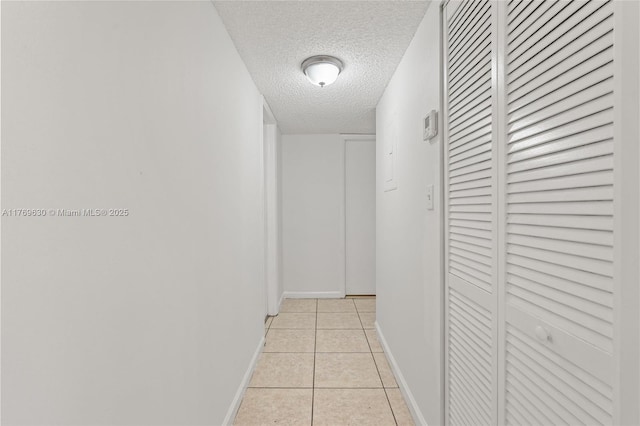 915 NE 199th St Unit 202-15, Miami, FL 33179 - hallway featuring light tile patterned flooring, baseboards, and a textured ceiling