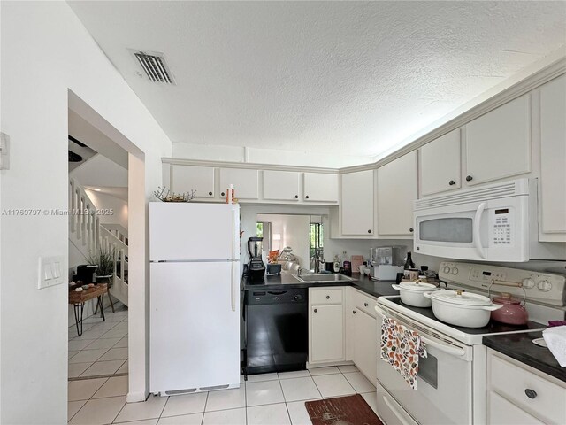 4306 N Carambola Cir N, Coconut Creek, FL 33066 - kitchen featuring white appliances, dark countertops, light tile patterned floors, a sink, and a textured ceiling