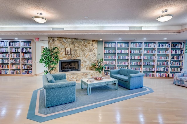 4306 N Carambola Cir N, Coconut Creek, FL 33066 - living room featuring a textured ceiling, bookshelves, wood finished floors, a fireplace, and built in shelves