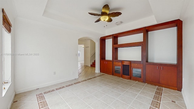 14214 SW 129th Path, Miami, FL 33186 - empty room featuring light tile patterned floors, a tray ceiling, arched walkways, a ceiling fan, and inlaid floor details