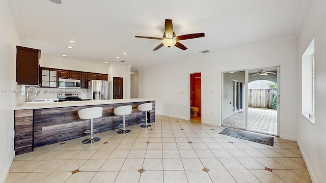 14214 SW 129th Path, Miami, FL 33186 - kitchen with appliances with stainless steel finishes, a sink, a ceiling fan, a kitchen bar, and a peninsula