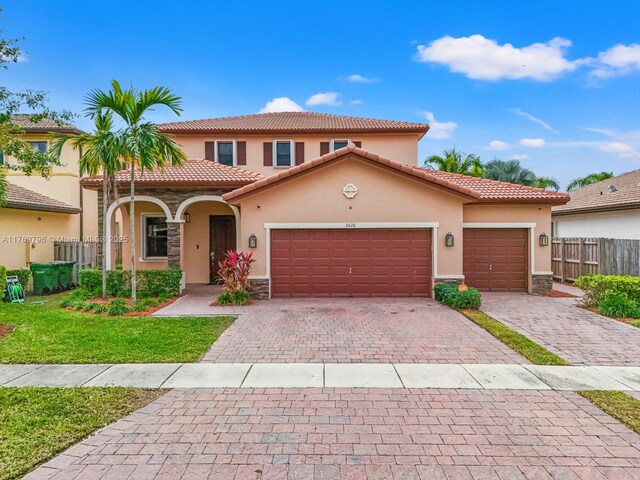 3626 SE 1st St, Homestead, FL 33033 - mediterranean / spanish-style home with a garage, decorative driveway, stone siding, stucco siding, and fence