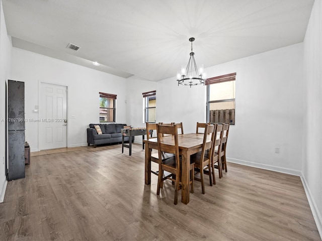 dining area featuring baseboards, visible vents, wood finished floors, and an inviting chandelier