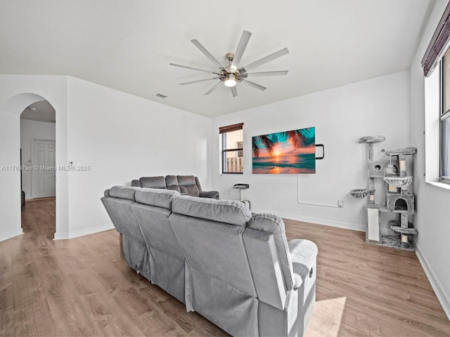 living room featuring a healthy amount of sunlight, arched walkways, ceiling fan, and wood finished floors