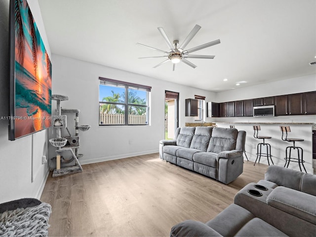 living area with baseboards, light wood-type flooring, ceiling fan, and recessed lighting