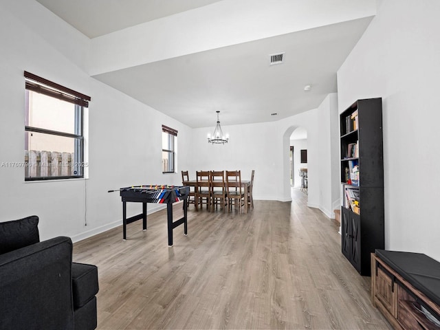 recreation room with visible vents, baseboards, an inviting chandelier, arched walkways, and light wood-type flooring